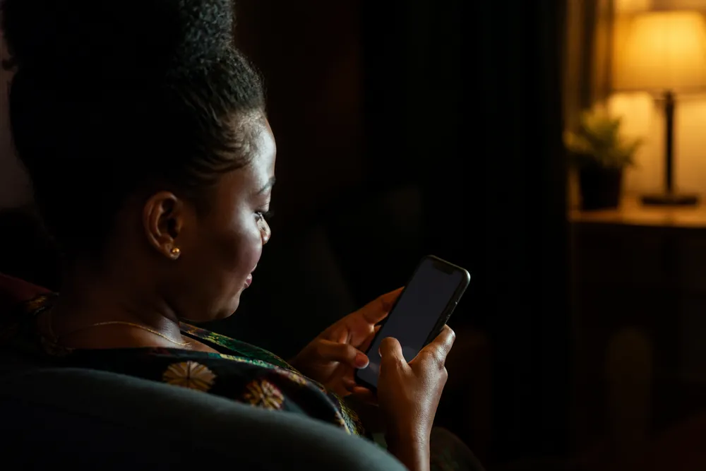 Photo: a woman types a chat message on her phone at home